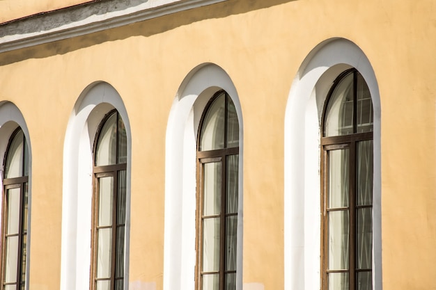 Three antique arched windows in a yellow-orange building.