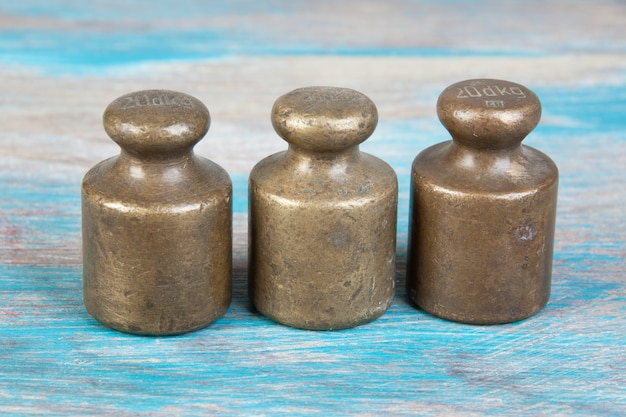 Three antique bronze weights for scales on blue wooden background. Copy space for text and food photography props.