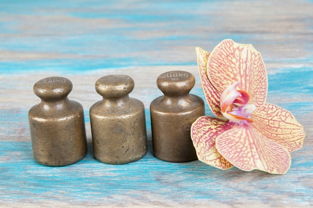 Three antique bronze weights for scales on blue wooden background. Copy space for text and food photography props.