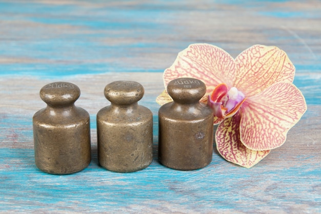 Three antique bronze weights for scales on blue wooden background. Copy space for text and food photography props.