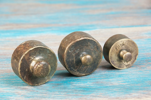 Three antique bronze weights for scales on blue wooden background. Copy space for text and food photography props.