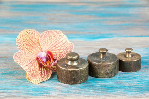 Three antique bronze weights for scales on blue wooden background. Copy space for text and food photography props.