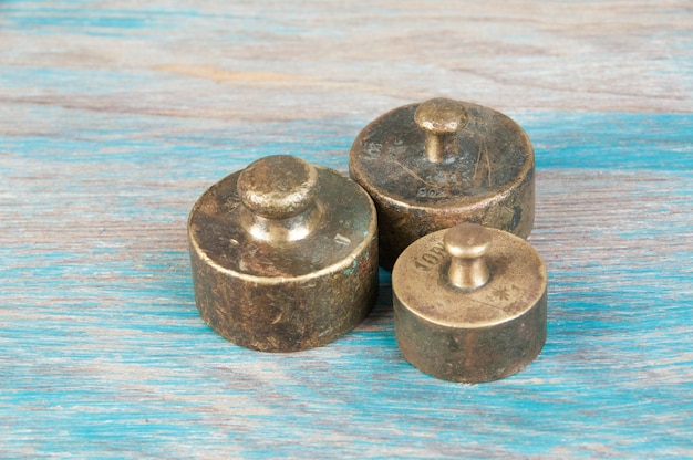 Three antique bronze weights for scales on blue wooden background. Copy space for text and food photography props.