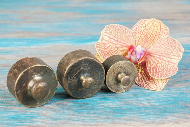 Three antique bronze weights for scales on blue wooden background. Copy space for text and food photography props.