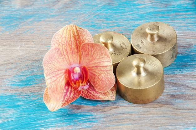 Three antique bronze weights for scales on blue wooden background. Copy space for text and food photography props.