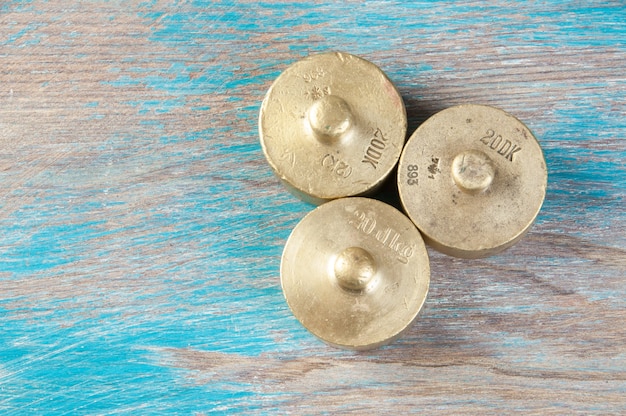 Three antique bronze weights for scales on blue wooden background. Copy space for text and food photography props.