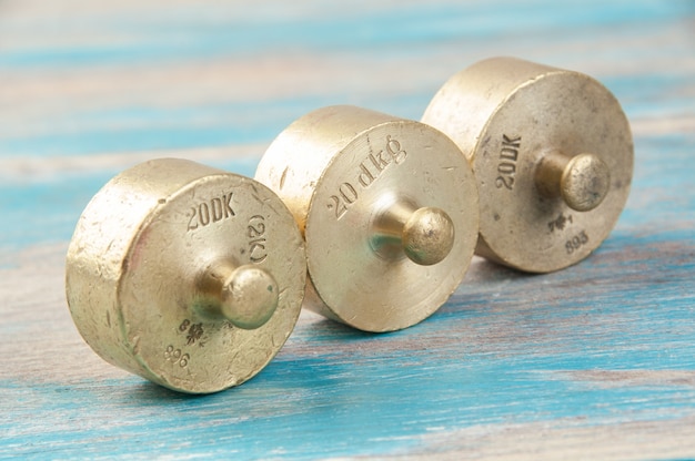 Three antique bronze weights for scales on blue wooden background. Copy space for text and food photography props.