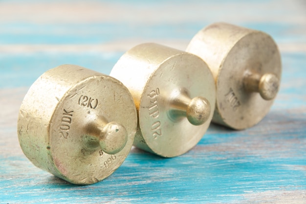 Three antique bronze weights for scales on blue wooden background. Copy space for text and food photography props.