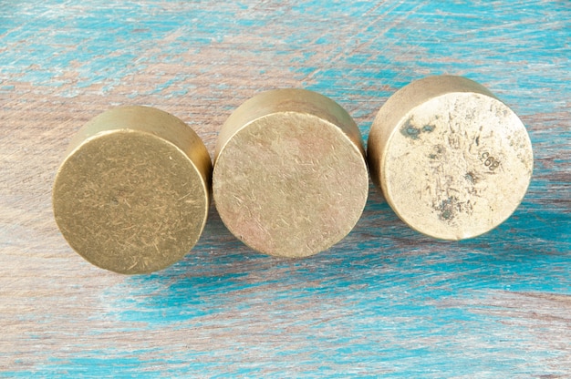 Three antique bronze weights for scales on blue wooden background. Copy space for text and food photography props.