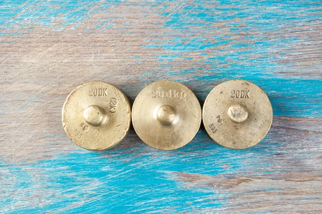 Three antique bronze weights for scales on blue wooden background. Copy space for text and food photography props.