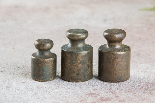 Three antique bronze weights for scales on concrete background. Copy space for text and food photography props.