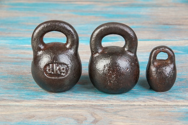 Three antique iron weights for scales on blue wooden background. Copy space for text and food photography props.