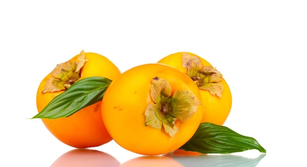 Three appetizing persimmons with green leaves isolated on white