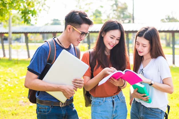 Three Asian young campus students enjoy tutoring and reading books together