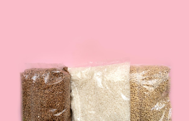 Three bags with groats on a pink background Victim assistance concept Buckwheat rice barley