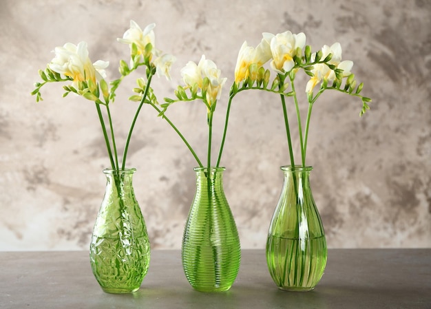 Three beautiful bouquets of fresh freesia in vases on table