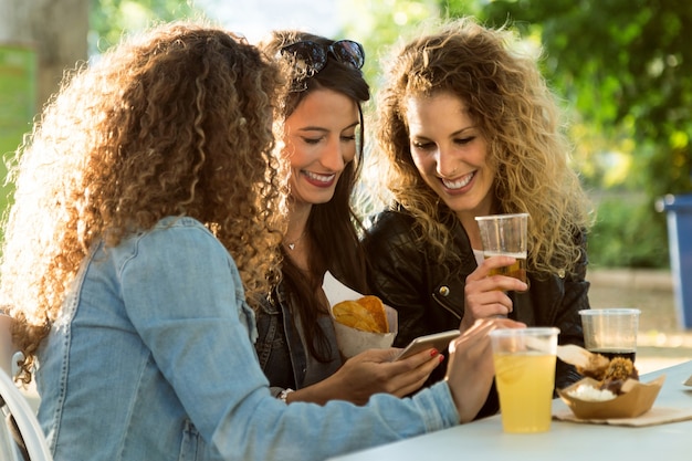 Three beautiful young women using they mobile phone in the street.