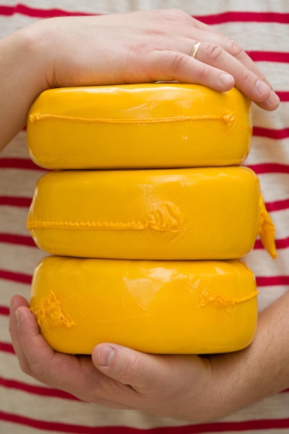 Three big organic cheese heads in yellow vacuum package in man's hands Food concept