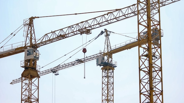 Three big yellow building crane on construction site morning sky background