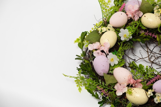 Three blue spotted chicken eggs and a wreath of willow twigs on a white background top view