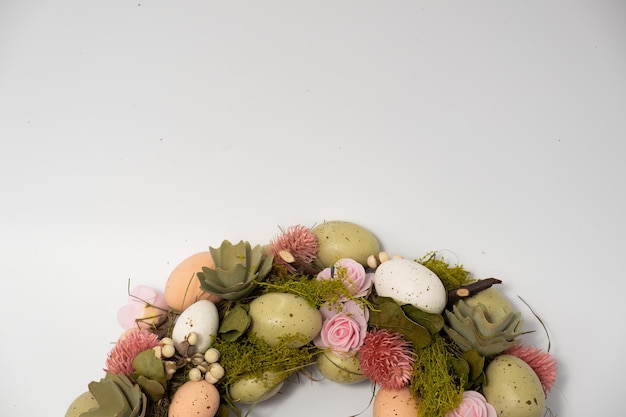 Three blue spotted chicken eggs and a wreath of willow twigs on a white background top view