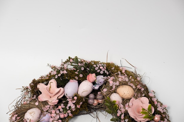 Three blue spotted chicken eggs and a wreath of willow twigs on a white background top view