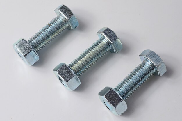 Three bolts with nuts screwed on them. White background.