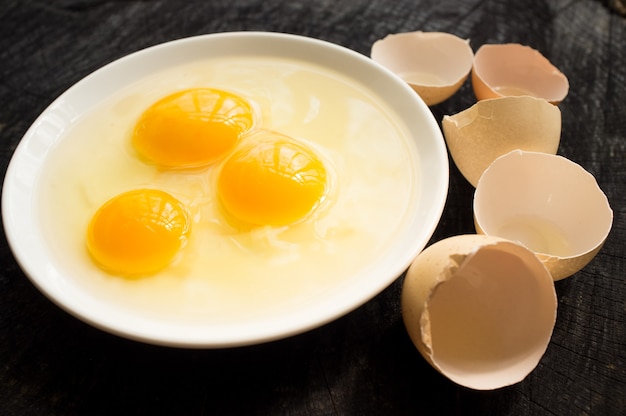 Three broken eggs and cracked shell on dark wooden desk