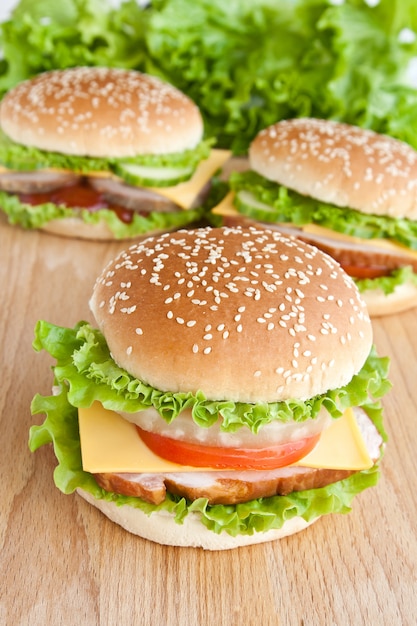 Three burger with meat and vegetables on wood plate