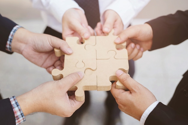 three businessman hand hold trying to connect Jigsaw wooden puzzle piece. one part of whole. symbol of association and connection. success and business solution strategy