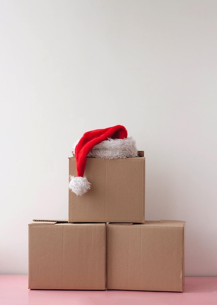 Three cardboard boxes are stacked one on top of the other there is a red Santa Claus hat on top.