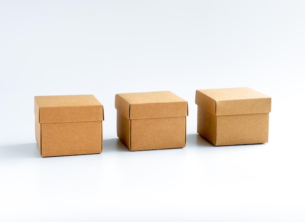 Photo three cardboard boxes isolated on white background carton gift box presents square kraft paper box with lid on top delivery parcel packaging with online shopping and shipping concepts