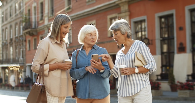 Three Caucasian senior female friends standing in city center