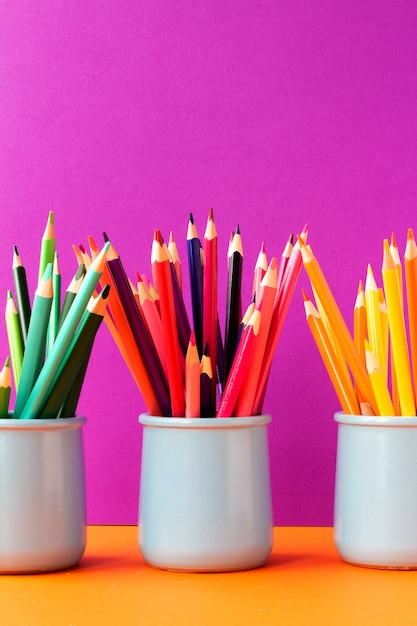 Three ceramic glasses with colored pencils. Back to school concept. Education background.