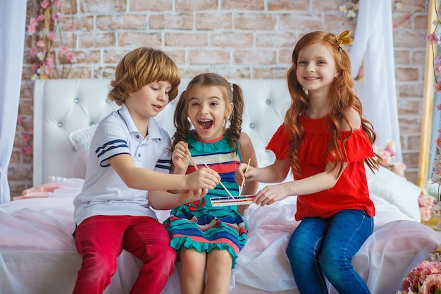 Three cheerful kids are sitting together and painting easter egg. Happy Easter.Spring holidays, tradition and people concept. Diligent pupils painting Easter egg.