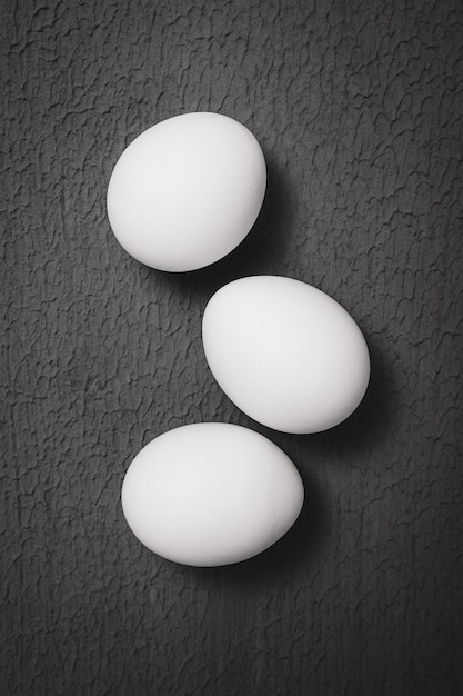 Three chicken eggs on a textured surface black and white photo