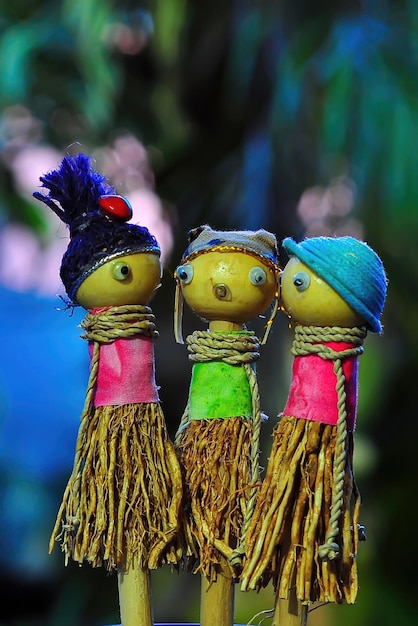 Three children's toy dolls made of wood and straw on a blurred background