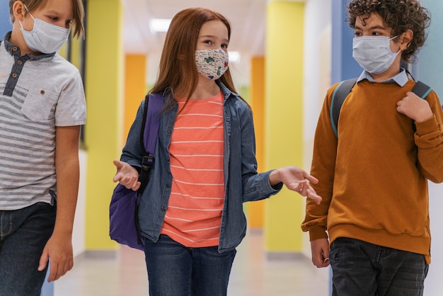 Three children on school hallway with medical masks