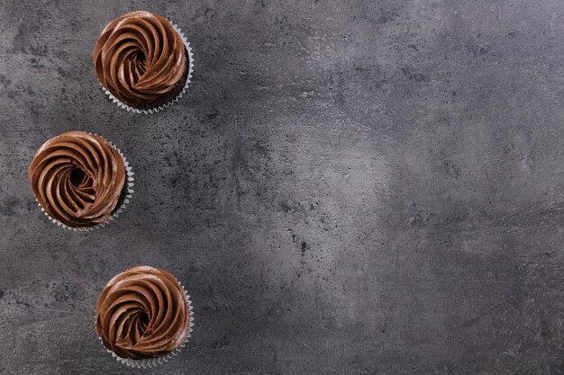 Three chocolate cupcakes on grey background