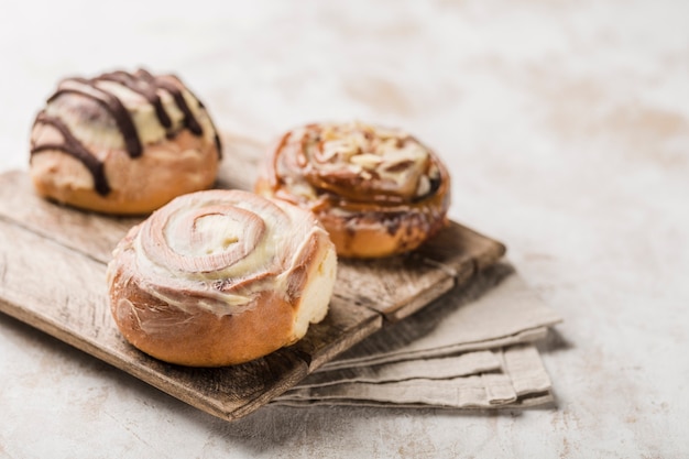 Three Cinnabon buns on a wooden Board with a napkin on a light background. American classic bun.