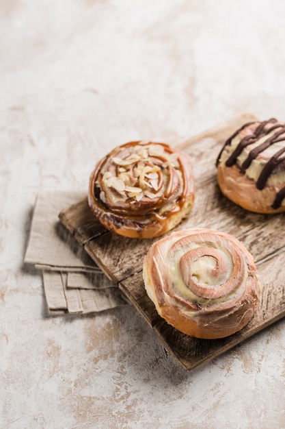 Three Cinnabon buns on a wooden Board with a napkin on a light background. American classic bun.