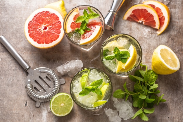 Three colorful gin tonic cocktails in whiskey glasses on bar counter in pup or restaurant - top of view.