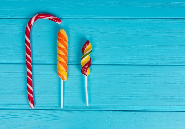 Three colorful tasty lollipops on wooden turquoise table