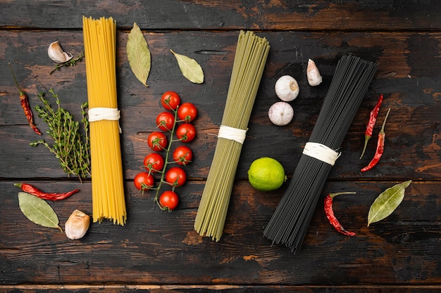 Three colors dry raw pasta set, on old dark  wooden table background, top view flat lay