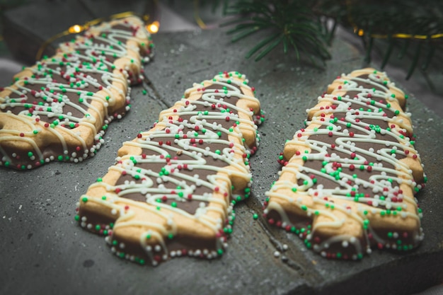 Three cookies in the shape of a Christmas tree with chocolate and colored sprinkles balls