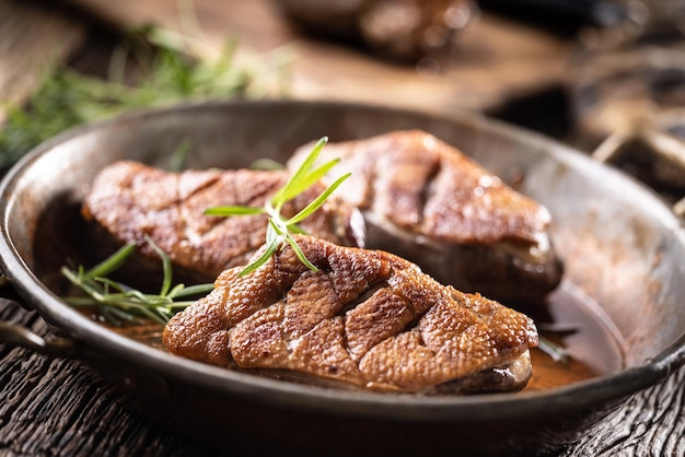 Three crispy duck breasts baked in an old rustic pan