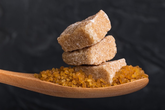 Three cubes of crushed cane sugar in a wooden spoon