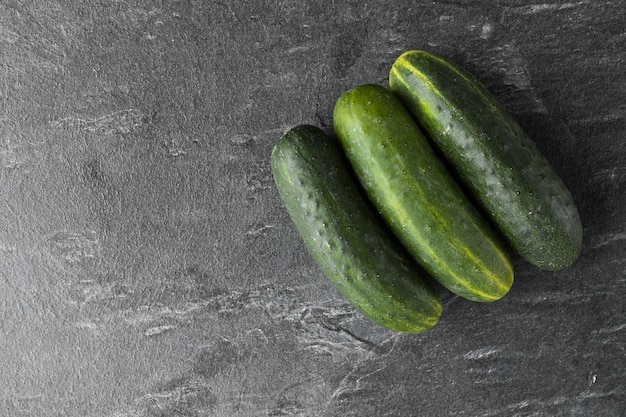 Three cucumbers on dark background