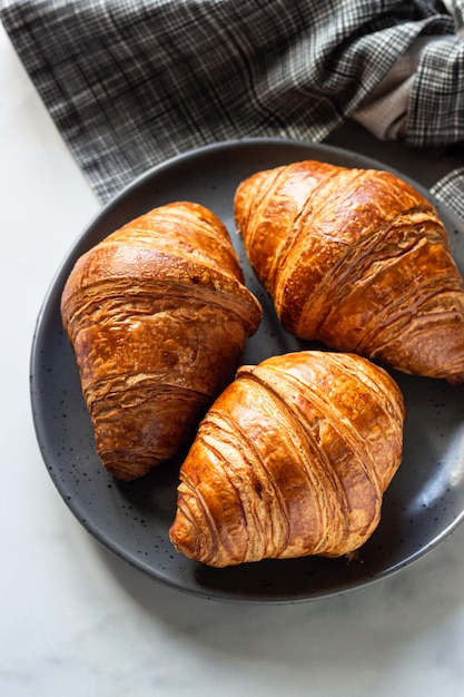 Three delicious fresh croissants on a ceramic plate