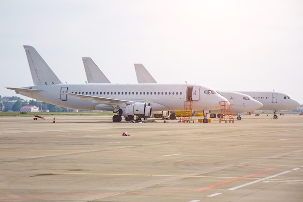 Three different narrowbody aircraft parked at the airport are lined up